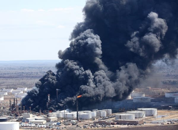 Thick smoke pours from the fire at the oil refinery.