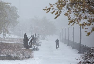 A person walks in the distance in a park with snow on the ground.