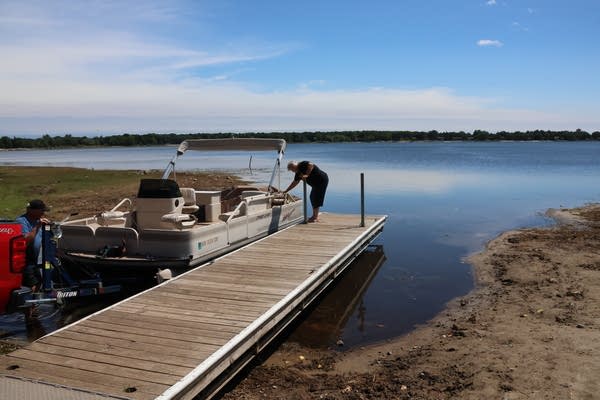 People stand on a dock next to a boat.