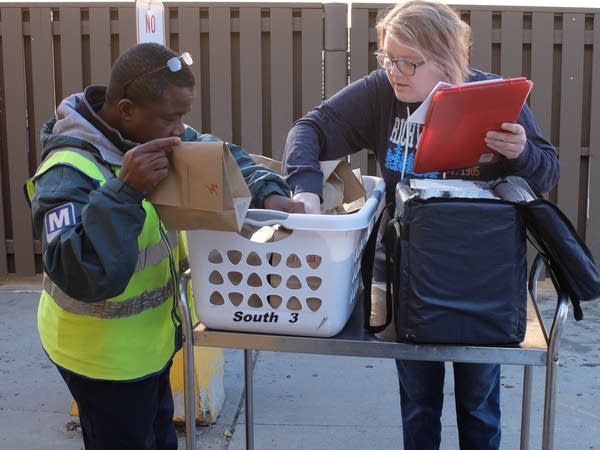 two people arrange a basket filled with paper sacks