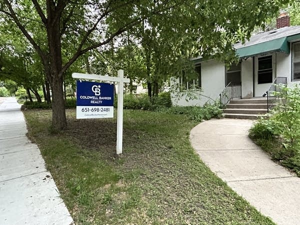 A sign in front of a house for sale.