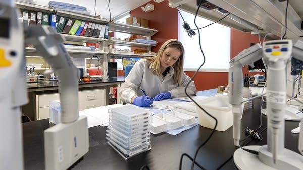 Technician writes down notes at a lab table