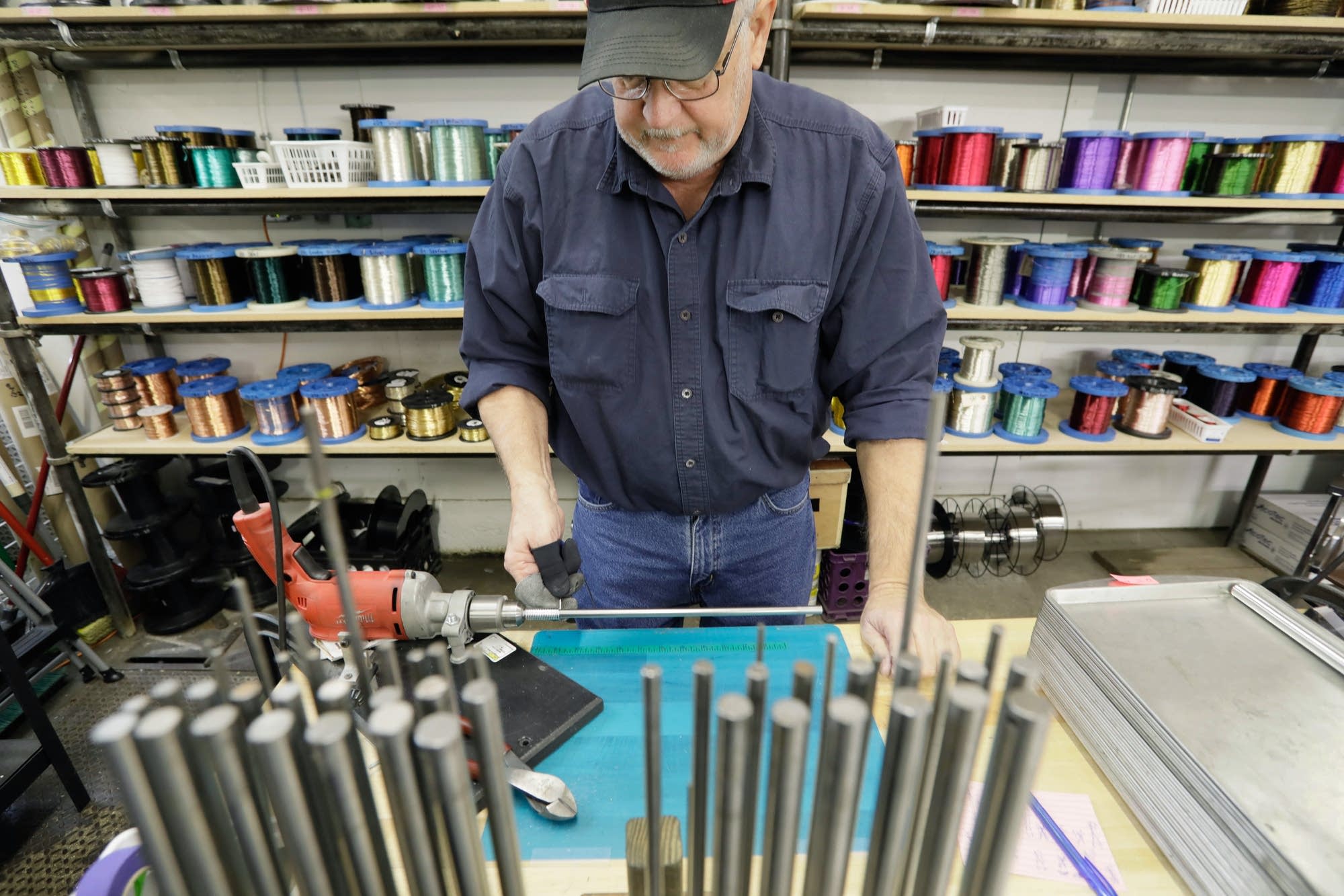 Roger Dauner uses a stationary drill to wind wire around a steel dowel.