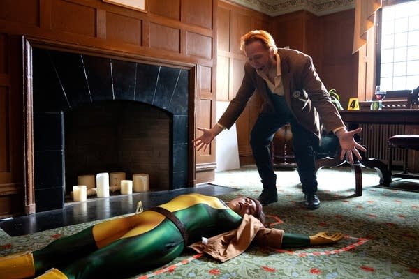 an actor reacts expressively to a staged mystery murder scene