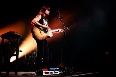A musician sings and plays guitar onstage