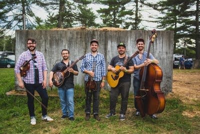 Five guys with stringed instruments stand together for a group photo