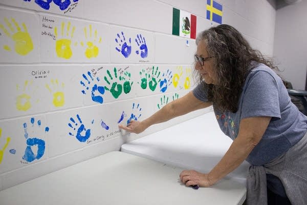 A person points at a wall with paint hands.