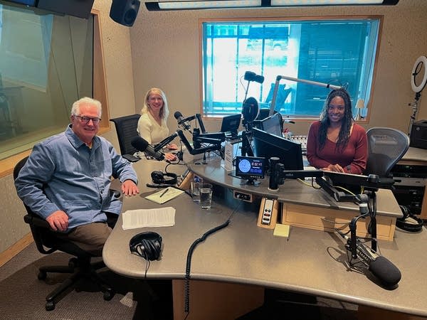 three people smiling in a broadcast studio