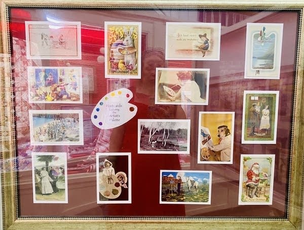 Vintage postcards are displayed behind glass. They all have animals near or holding paint palettes.
