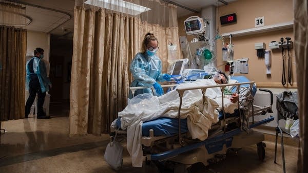  A health care worker tends to a COVID-19 patient in Apple Valley, California. Rural hospitals are struggling to hire staff amid surging case numbers.