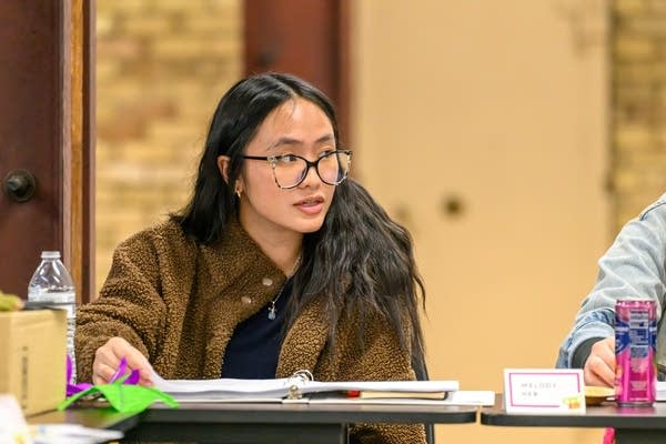 A woman sits at a table with a script in front of her.