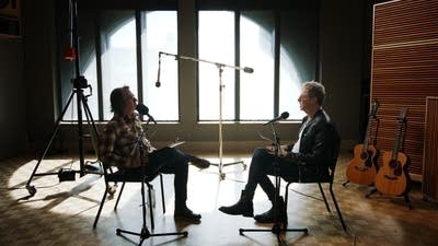 Two men have a conversation in a recording studio
