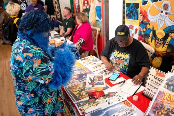 a man dressed in cosplay getting special artwork signed by another man