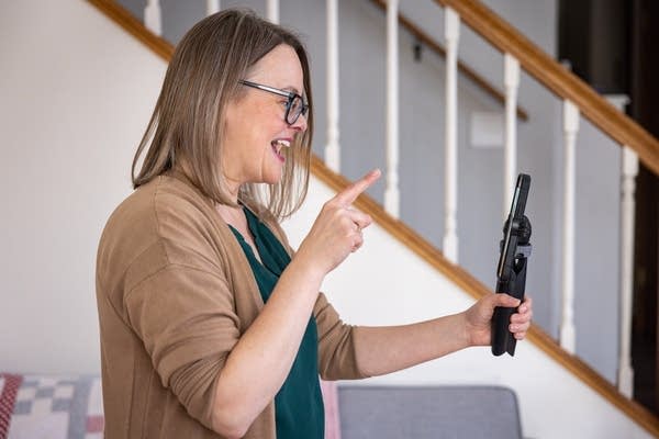 A woman uses a handheld stabilizer and smartphone to record a video