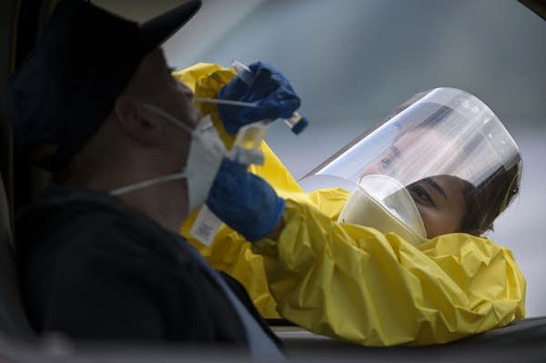 A person wearing a personal protective equipment at a drive thru site