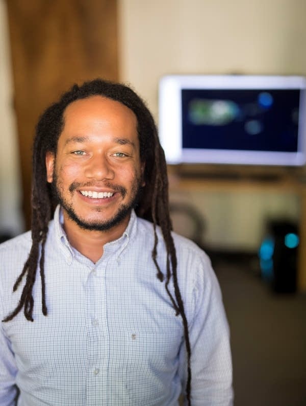 Justin Dunnavant smiles for a photo with a computer monitor in the background.