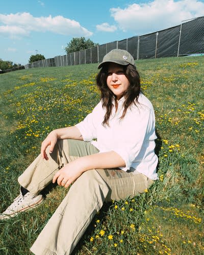 Lucy Dacus sitting on grass and posing for a photo