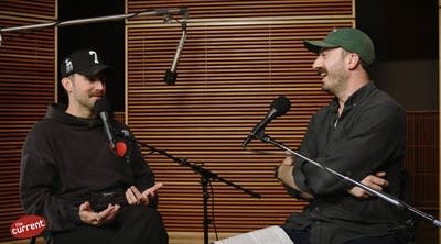 Two men have a conversation in a recording studio