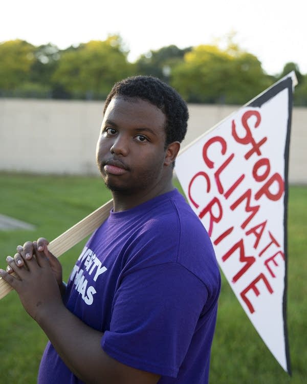 A teenage boy holds a sign over his shoulder