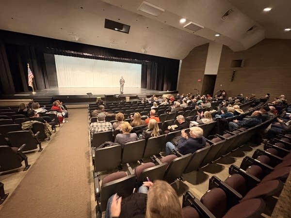 People in an auditorium listen to a man on stage