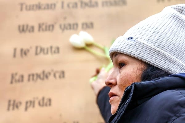 A person touches a wall with names