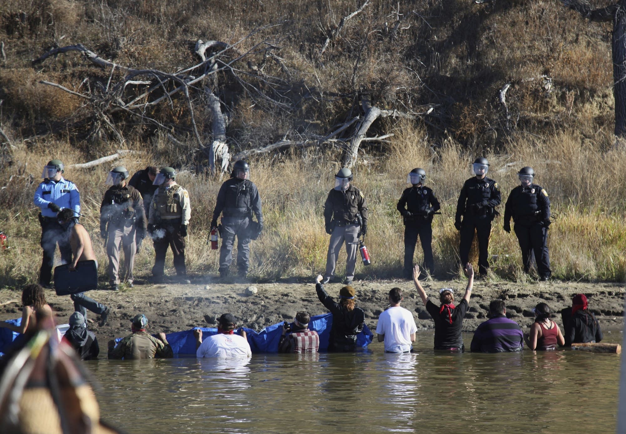 Protesters wade in a creek to demonstrate.
