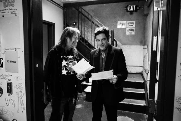 Two musicians look over song lyrics and set list backstage