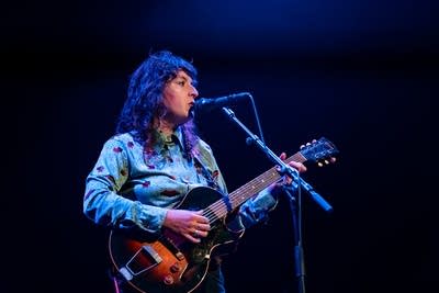 A woman sings and plays guitar onstage in a music venue