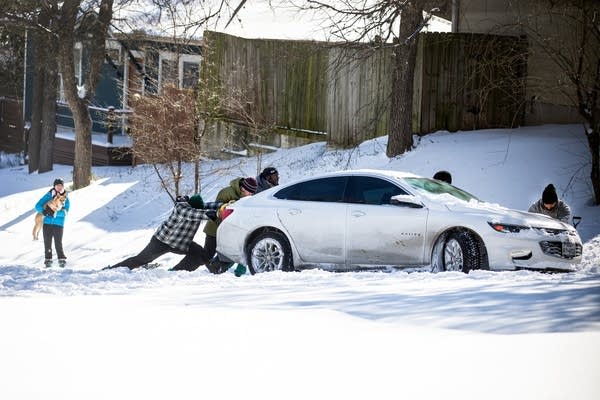 People push a car out of the snow on Feb. in Austin, Texas. Winter storm Uri has brought historic cold weather to the state, causing traffic delays and power outages.
