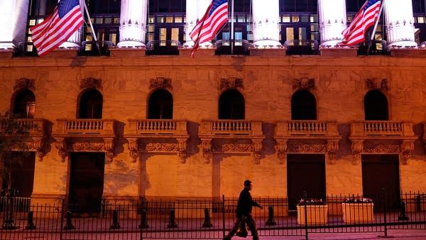 A man walks  in front of the New York Stock Exchange in the early hours of the morning.