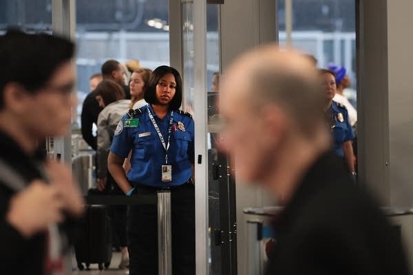 A TSA worker screens passengers and airport employees in Chicago.