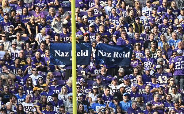 A crowd of people holds up Naz Reid rally towels in a stadium.