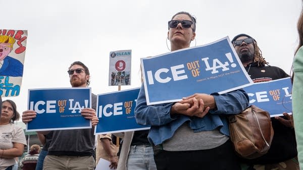 People hold signs that say "ICE out of LA"