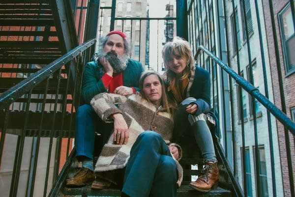 Three people sit together on the stairs of a fire escape