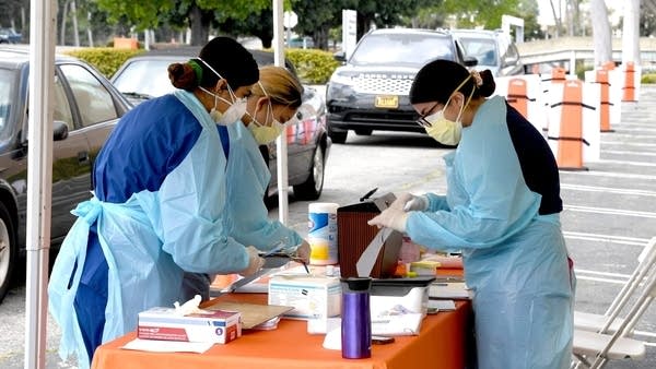 Workers wearing personal protective equipment host drive-thru testing for the COVID-19 in the Sherman Oaks neighborhood of Los Angeles, California. 