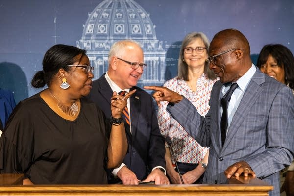 Two Black legislators jokingly point at each other