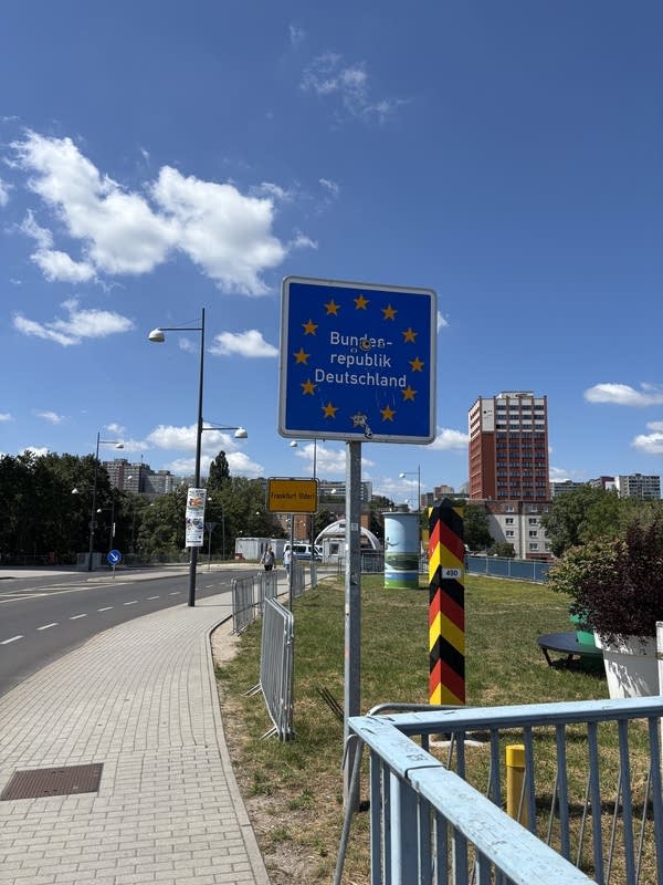 A post with red, yellow, and black stripes and a sign with the flag of the EU.