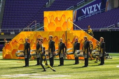 A marching band performs on the field of a football stadium.