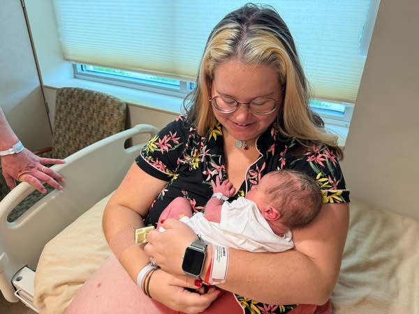 A woman cradles a newborn baby.