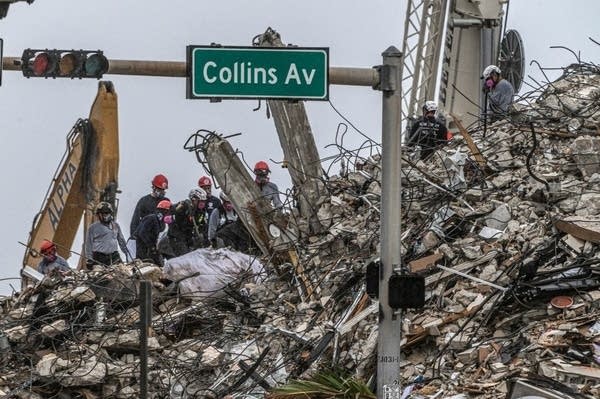 Rescue workers work at the site of a collapsed building.