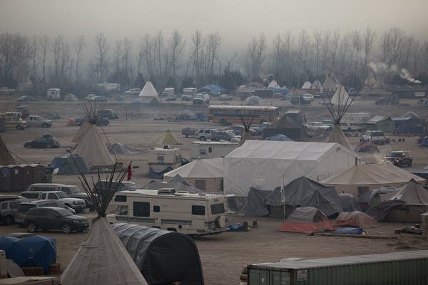 Morning fog mixed with campfire smoke over an encampment.