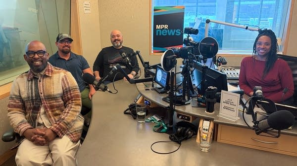 four people smiling in a broadcast studio