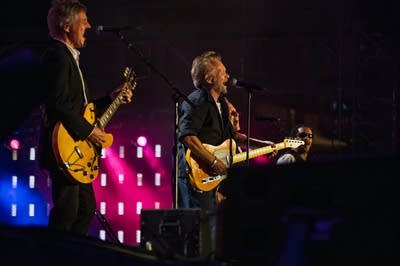 Four musicians performing together on a large outdoor stage