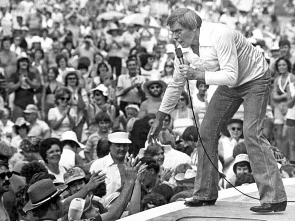 Singer Tom T. Hall reaching out to fans while singing onstage