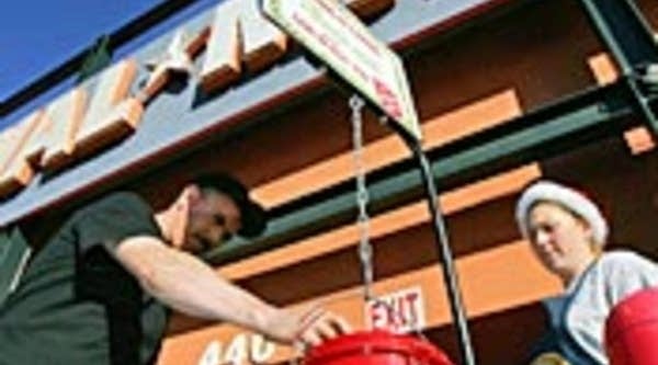 A customer coming out of a Wal-Mart store donates to the Salvation Army as a bell ringer watches.