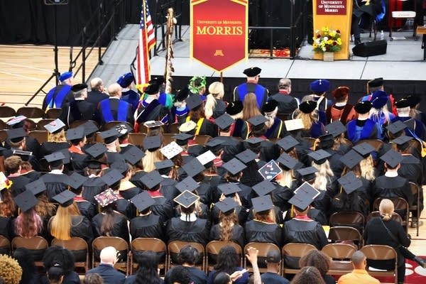 Graduates sit with caps and gowns