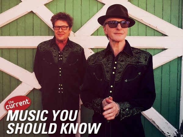 Two men standing outside a barn door