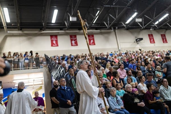 A bishop carries a cross