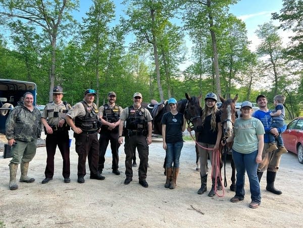 Two riders and their horses pose with deputies who helped rescue them.