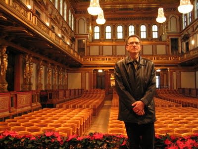 John Birge stands at the front of a concert hall.